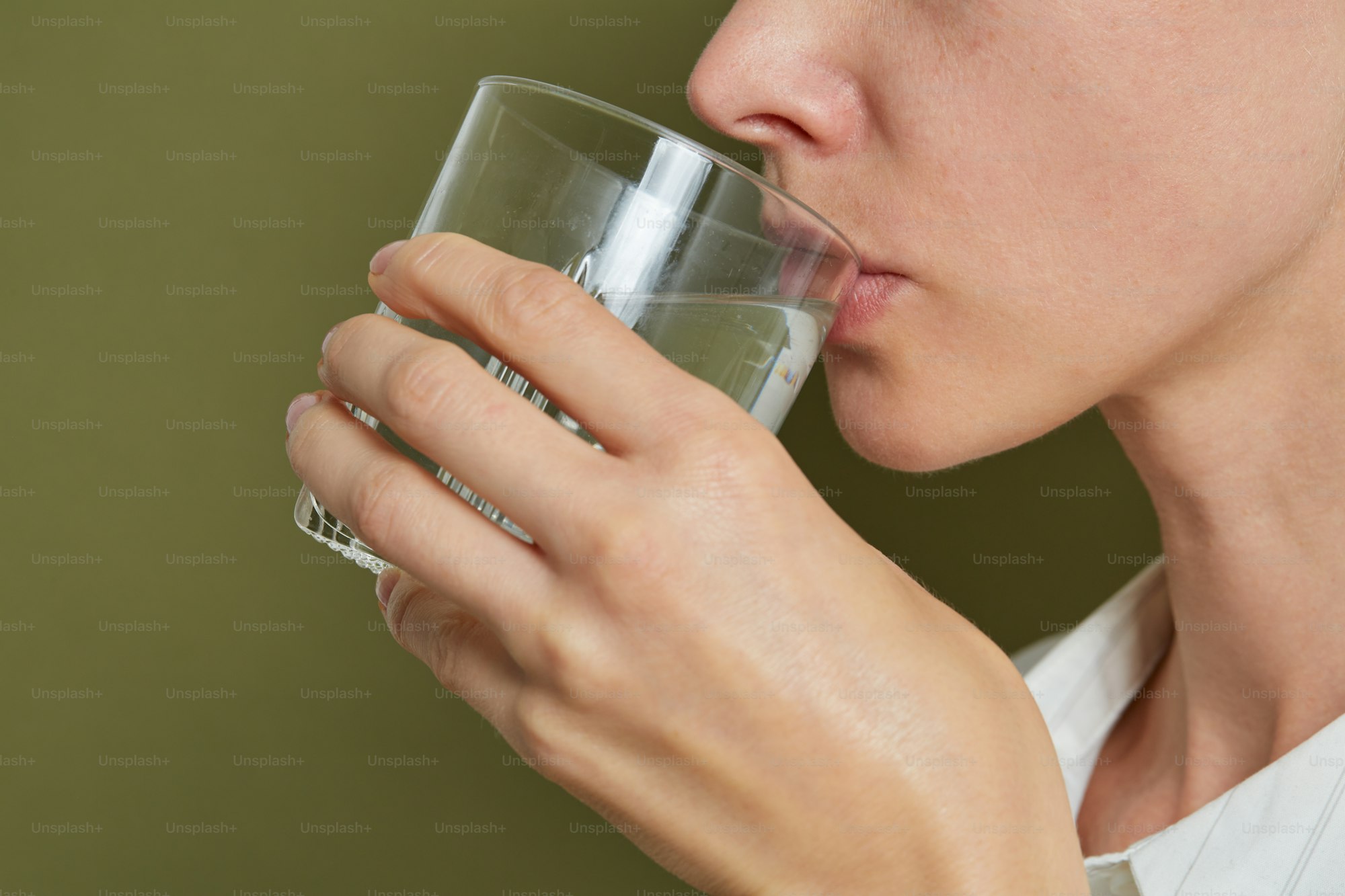 Persona sirvi&eacute;ndose un vaso de agua mineral en la cocina para mantener una buena hidrataci&oacute;n y ayudar a controlar el &aacute;cido &uacute;rico