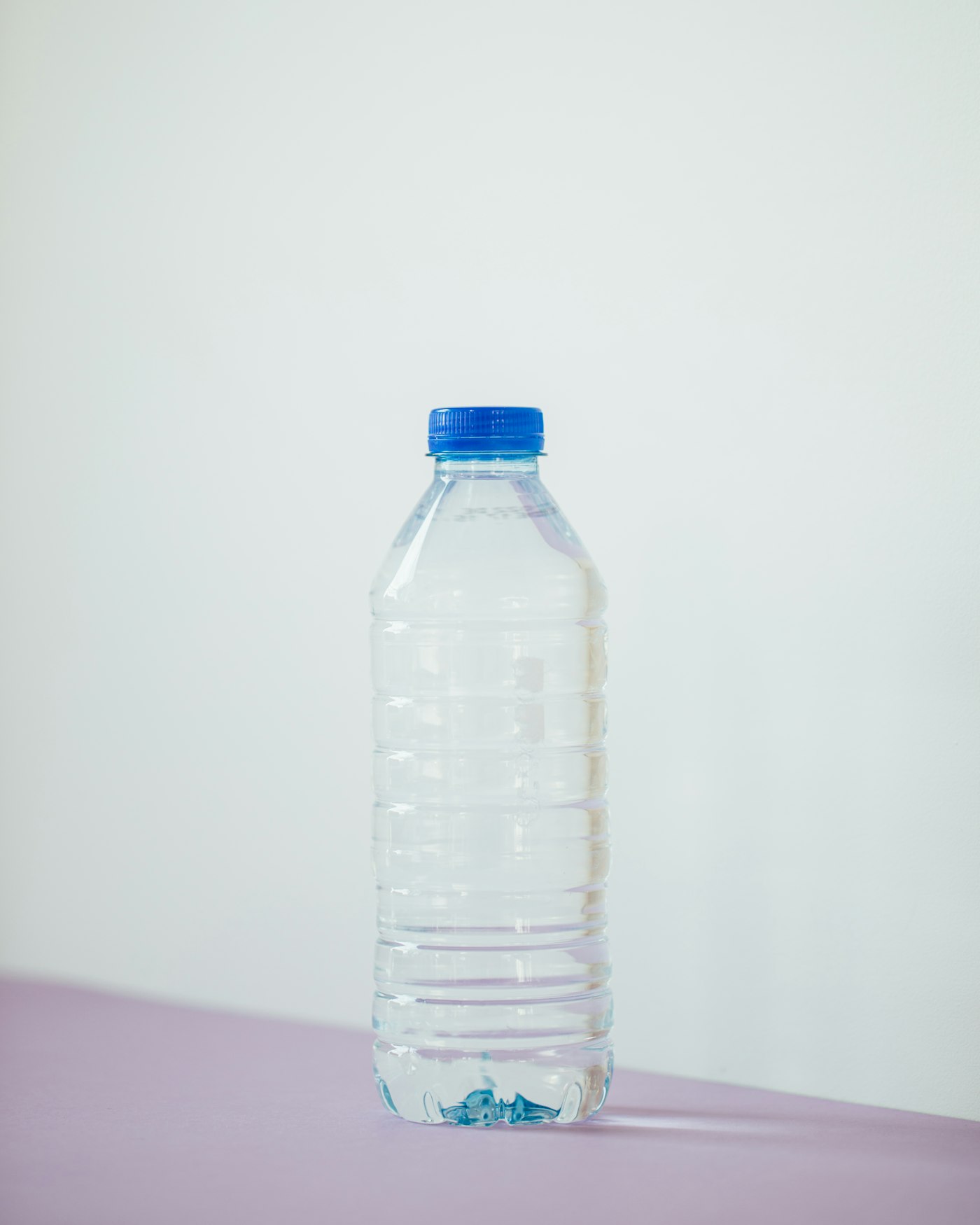 Botella de agua mineral de pl&aacute;stico PET con tap&oacute;n azul sobre una superficie clara, ilustrando la fecha de consumo preferente del agua embotellada