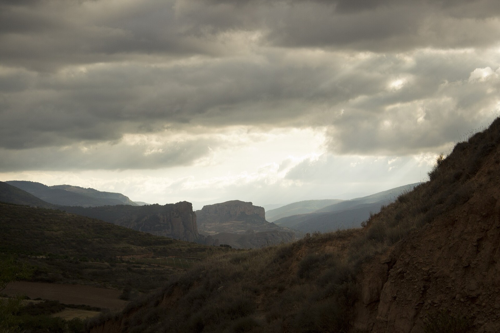 Las pe&ntilde;as de conglomerado de Pe&ntilde;a Bajenza y el Castillo de Viguera bajo un cielo de nubes de tormenta, en el valle del r&iacute;o Iregua, La Rioja