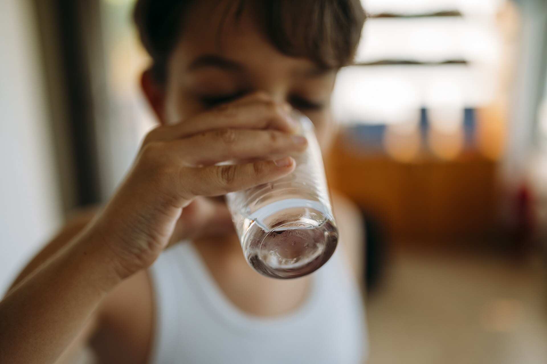 Persona bebiendo un vaso de agua en casa, un gesto cotidiano que en exceso puede diluir el sodio de la sangre